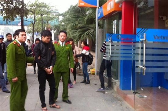 Đại (giữa) bị cảnh sát dẫn giải chỉ vị chỉ 2 cây ATM định trộm bên phố Nguyễn Chí Thanh.