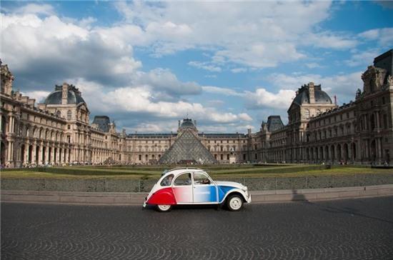 Hình ảnh chiếc taxi màu mè chạy qua Bảo tàng Louvre.