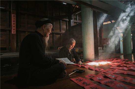 Hai cụ già trong trang phục truyền thống ngồi viết câu đối để chuẩn bị đón năm mới ở Long Sơn, Bà Rịa - Vũng Tàu. Ảnh: JetHuynh/Picfair.