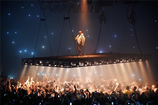 Fan nam bị xua xuống sau khi cố trèo lên sân khấu bay của Kanye West - Ảnh 1.