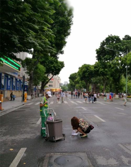 co gai tre cui xuong hot phan cho tren duong cho vao thung rac - 1