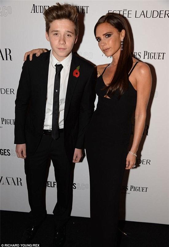 Picking up tips from his parents: Looking cool, calm and confidant as he posed up a storm alongside his mother, Brooklyn cut a slick figure in an immaculately tailored black suit, which he teamed with a matching tie and a crisp white shirt