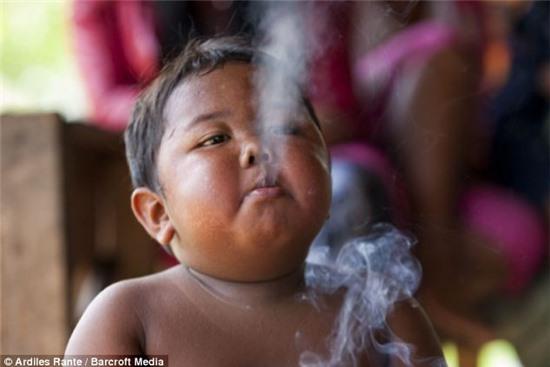 Destructive: The youngster was discovered in a poor village in Sumatra, Indonesia, puffing on a cigarette while riding his tricycle