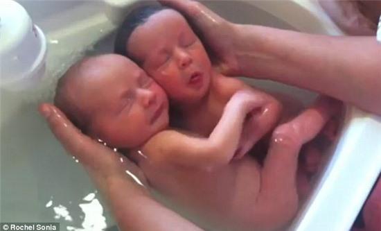 Close bond: A fascinating video shows a set of newborn twins locked in a tender embrace as they are bathed the very first time