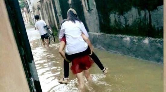 Nữ sinh để bố khiêng xe đạp, mẹ cõng qua đoạn đường ngập