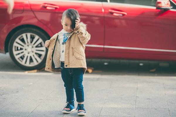 Xuống phố dạo chơi, cậu bé được bố cho diện trang phục màu đỏ rực rỡ kết hợp quần jeans xoắn gấu, áo khoác, sơ mi kẻ caro cùng slip-on.