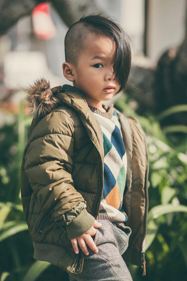 Chiếc quần màu xám tro được chọn kết hợp cùng áo len họa tiết hình học bắt mắt, phối hợp thêm áo khoác màu nâu rêu trầm mặc.