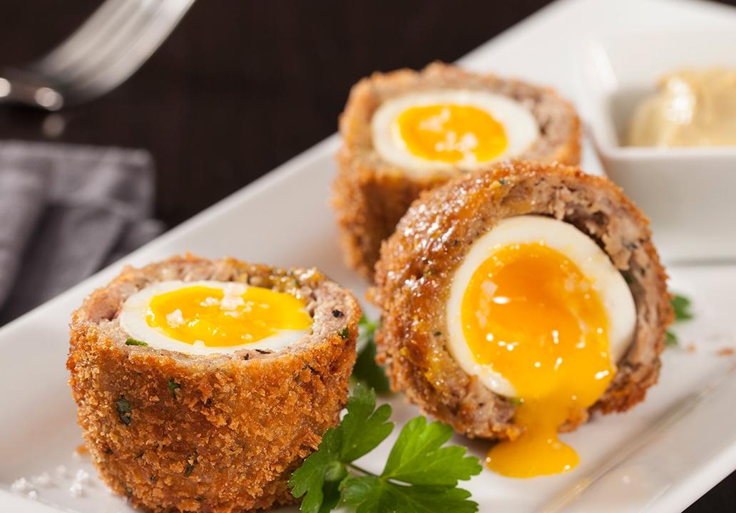 Anh: Bạn có thể tưởng tượng ra độ ngon của món Scotch Eggs bằng cách đọc phương pháp chế biến của nó. Những quả trứng được luộc sơ, nhúng vào nước lạnh rồi bóc vỏ rồi bọc với xúc xích trộn vụn bánh mì trước khi đem chiên giòn trong dầu nóng. Nếu làm khéo, bạn sẽ có món ăn tuyệt ngon với lớp thịt siêu ngon mà quả trứng vẫn còn lòng đào.