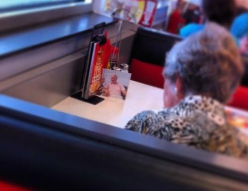 Bức ảnh trên được một nữ nhân viên tại nhà hàng Steak 'n Shake (Mỹ) chia sẻ. Mặc dù chồng đã mất từ lâu, song bà lão này vẫn hàng ngày mang theo ảnh của người bạn đời, đặt trên bàn và ngồi ăn cùng với ông. Câu chuyện tình yêu từng gây chấn động trên mạng và tấm hình này cũng được đăng tải trên hàng loạt tờ báo lớn.