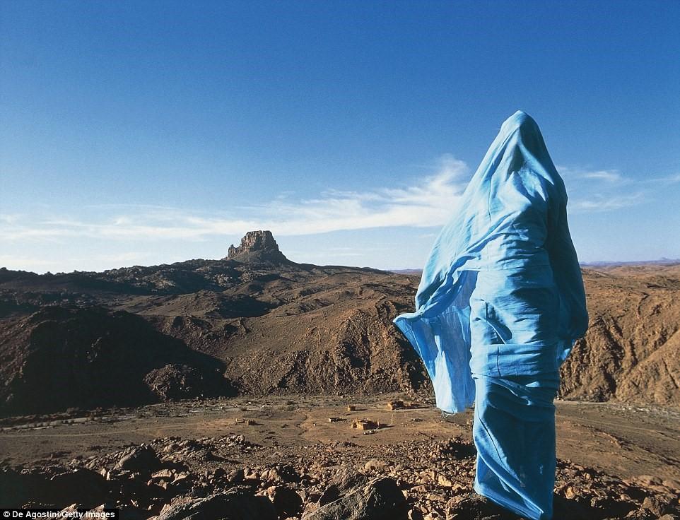 Một người Tuareg mặc trang phục màu xanh tươi sáng đứng trên dãy núi Hoggar của sa mạc Sahara, Algeria.  Ảnh: Deagostini/Getty Images.