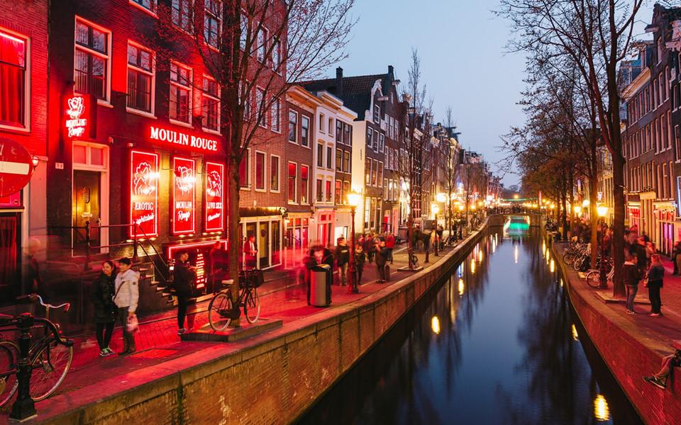 Quận đèn đỏ Amsterdam, Hà Lan: Hình ảnh quận đèn đỏ ở Amsterdam luôn mang màu sắc quyến rũ và cấm kỵ, thu hút sự tò mò của du khách đến với xứ sở hoa tulip. Ảnh: Red Light District Tours.