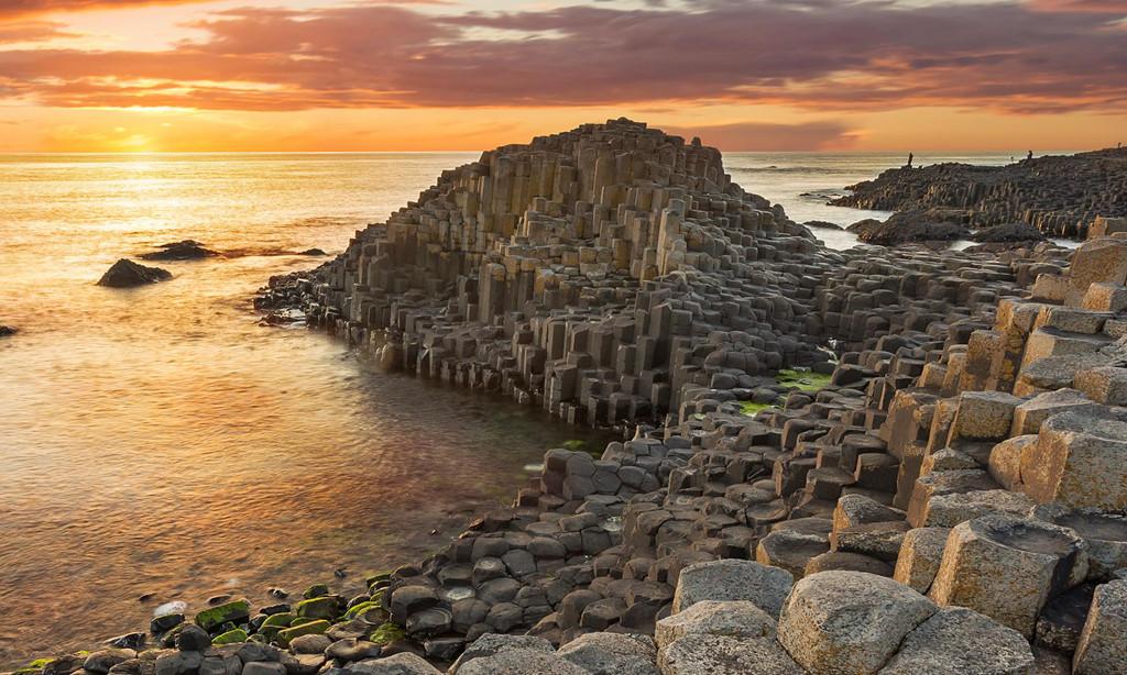Giant's Causeway (Ireland): Một vụ phun trào núi lửa thời tiền sử đã hình thành bãi đá có hình dạng kỳ lạ ở Bắc Ireland, tạo nên những cột đá núi lửa hình trụ giống đá lát đường. Đặc trưng địa lý khiến nơi này có tên “Giant’s Causeway” (Đường của người khổng lồ), gắn với truyền thuyết về người khổng lồ tên Finn. Ảnh: Newmarket Holidays.