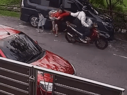 Clip: Người phụ nữ vừa xuống khỏi ô tô bị tên cướp giật balo kéo ngược về sau, con gái ‘reo vui’ vì tưởng mẹ đang đùa