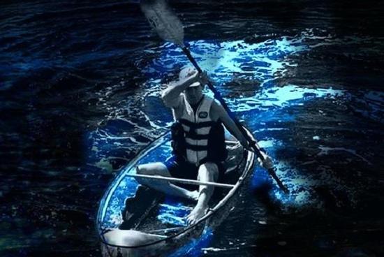 Chèo thuyền trong suốt giữa biển nước phát ánh sáng xanh