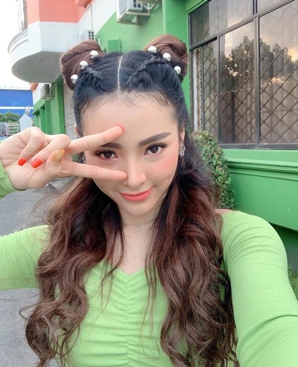 Phương Trinh Jolie diện áo xanh rực rỡ, tóc cột hai bên và tạo dáng nhí nhảnh.