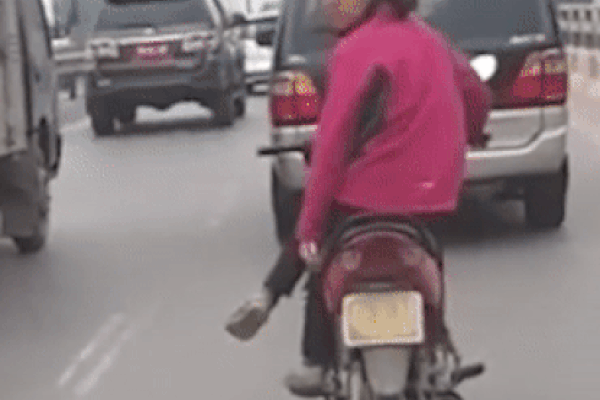 Clip: Nín thở nhìn người phụ nữ vắt chéo chân, chạy xe máy lạng lách giữa các ô tô như diễn xiếc