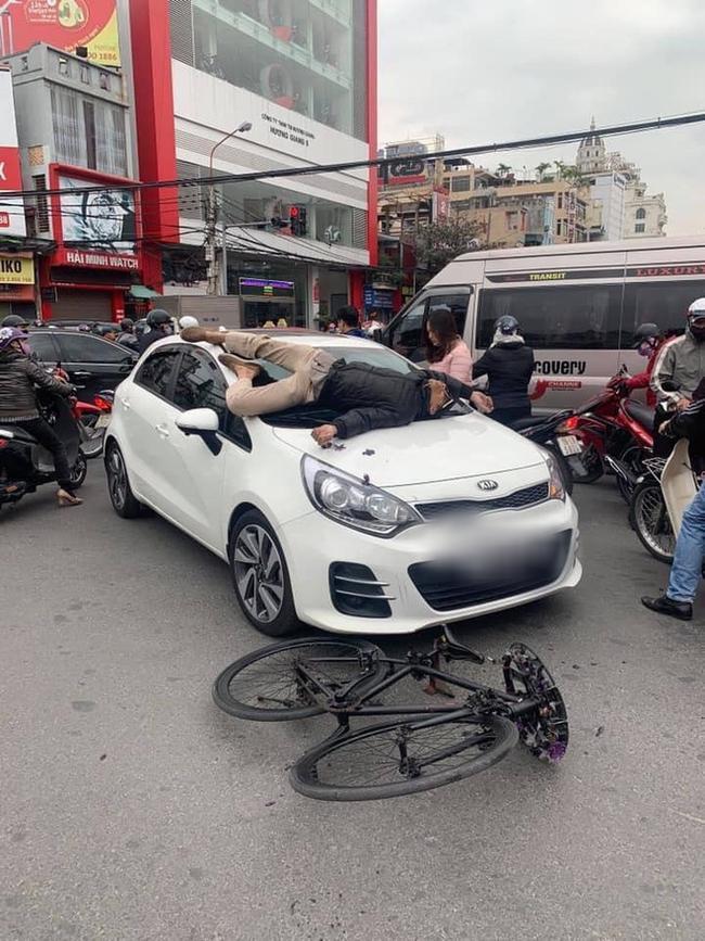 Va chạm giao thông nhưng không hòa giải được, chủ xe đạp leo lên nắp capo ô tô nằm... ăn vạ-1