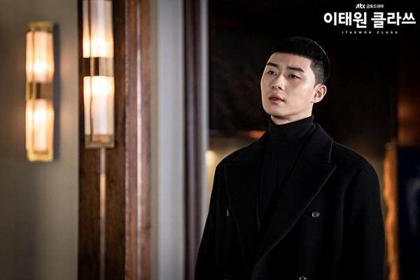 Đúng như dự đoán của fan, Park Sae Roy đạt được mục tiêu khi trở thành người đứng đầu tập đoàn lớn. Để phù hợp với phong cách doanh nhân, anh thường chọn combo khoác dáng dài phối cùng áo cổ lọ, skinny jeans và boots da lộn cao cổ. Nam diễn viên thường diện đồ nguyên cây đen để tăng độ "ngầu" và tỏ ra nguy hiểm trước chủ tịch Jangga - kẻ thù của Park Sae Royi. Ảnh: JTBC.