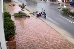 Cậu bé dừng xe nhặt rác dưới rãnh bẩn, khơi thông cống tắc dưới trời mưa