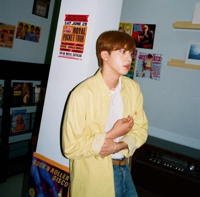 Công thức phối đồ theo phong cách hoài cổ với các tông màu pastel được BTS tận dụng. Jin diện sơ mi dáng rộng cùng quần jeans và áo phông. Nam ca sĩ kết hợp với dây chuyền hoa cúc trị giá 58 USD để tạo thêm điểm nhấn. Ảnh: Theqoo.