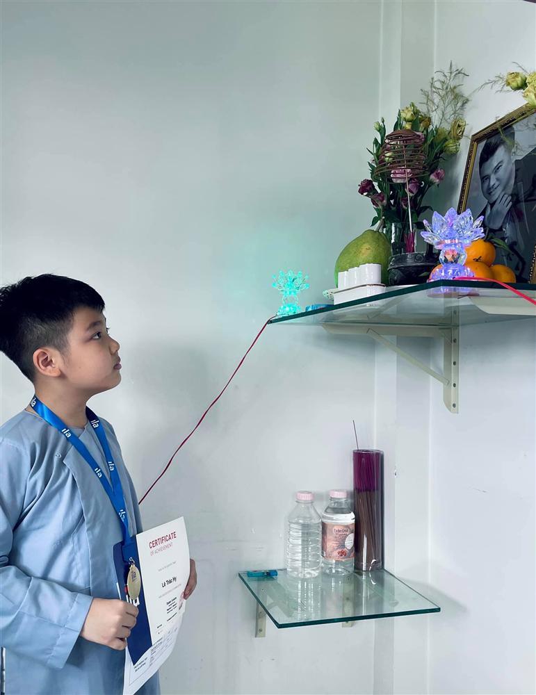 2 con Vân Quang Long cầm giấy khen đứng trước bàn thờ bố-2