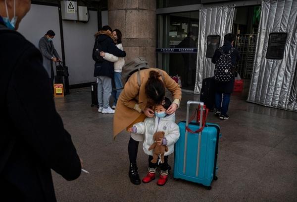 Một người phụ nữ chỉnh khẩu trang cho đứa trẻ khi chờ lên tàu ở Bắc Kinh. Ảnh: Getty Images.