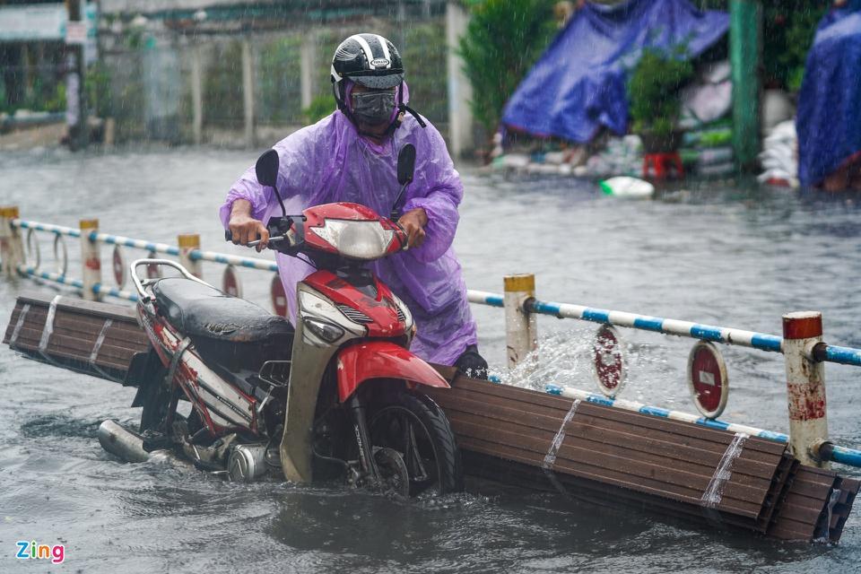 Người dân chật vật đẩy bộ xe bị chết máy dưới màn mưa mù mịt. Nhiều người cho biết đoạn đường này cứ mưa là bị ngập. Xung quanh còn có đường Lê Văn Thọ và Phạm Văn Chiêu cũng chung cảnh tương tự.