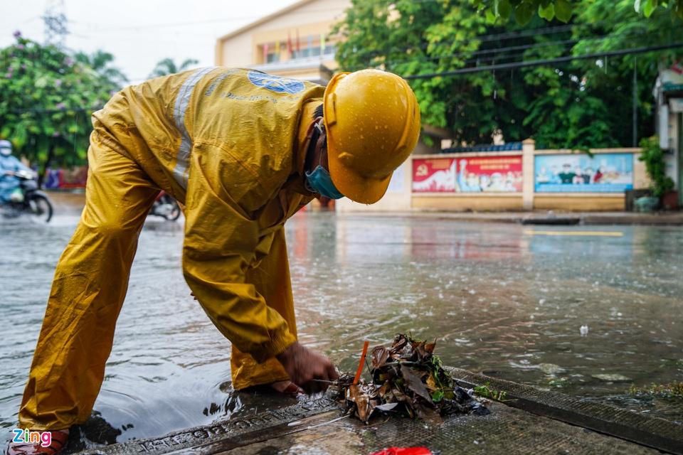 Nhân viên công ty Thoát nước đô thị TP.HCM phải nhặt từng chiếc lá tại các miệng cống để giúp nước thoát nhanh hơn.