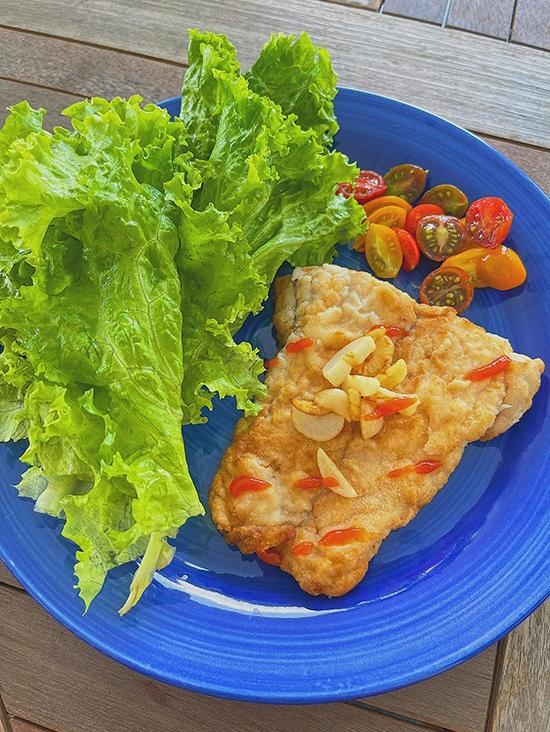 Bữa trưa, nàng siêu mẫu làm món cá chẽm chiên giòn, ăn kèm với rau xà lách, cà chua bi. Cá được tẩm bột chiên lên nên có lớp vỏ giòn giòn, bên trong cá mềm thơm, ngọt thịt, chấm với tương ớt.