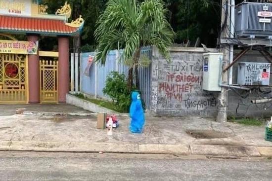 Em bé mặc đồ bảo hộ một mình đợi xe, lỉnh kỉnh đồ đạc đi cách ly