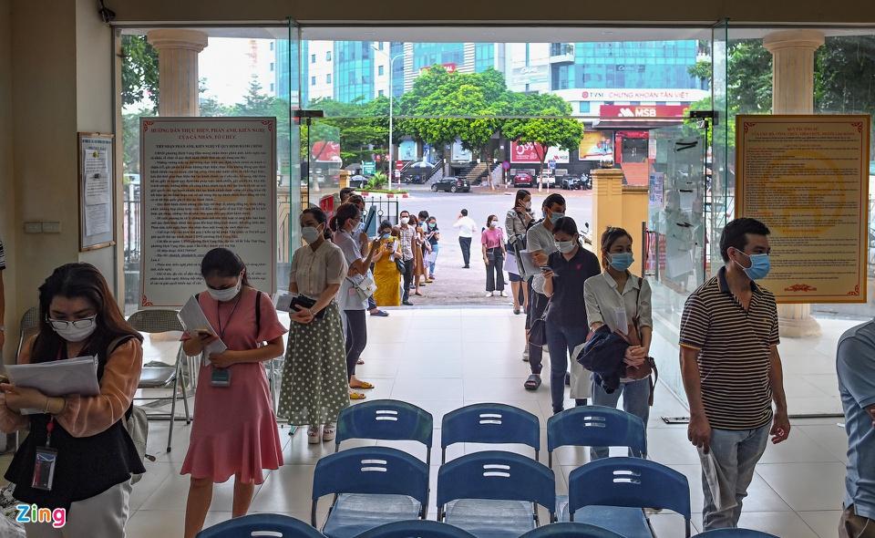 Cán bộ tại phường bố trí người dân đứng xếp hàng giãn cách tránh việc tập trung đông.