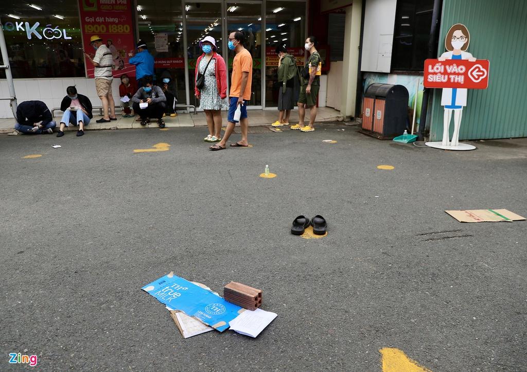 Sáng 21/8, nhiều người dân TP.HCM đổ ra các chợ và siêu thị mua sắm thực phẩm, hàng hóa. Tại siêu thị Big C (quận 10), nhiều người đã phải dùng gạch, dép để giữ chỗ xếp hàng vào mua sắm.