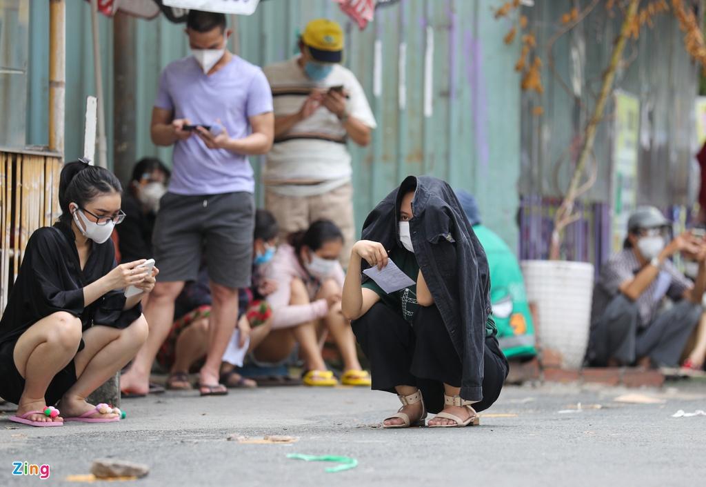 Nhiều người kiên trì ngồi đợi giữa trời nắng để không mất số thứ tự.