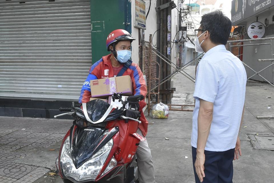 Phó thủ tướng Vũ Đức Đam trò chuyện với shipper Trần Bảo Tỷ (ở phường Tân Định, Quận 1) đang chờ nhận hàng đi giao. Shipper này nói công ty của anh cho nhân viên giao hàng ăn, ở tập trung và xét nghiệm nhanh 3 ngày/lần.