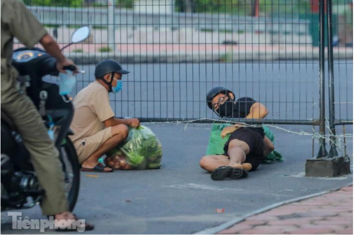 Một số người tìm cách vượt khe hở giữa hàng rào để luồn lách qua.