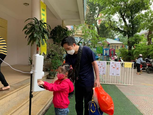 Học sinh và phụ huynh đo thân nhiệt trước khi vào trường Mầm non Hoa Hồng, quận Đống Đa, Hà Nội.