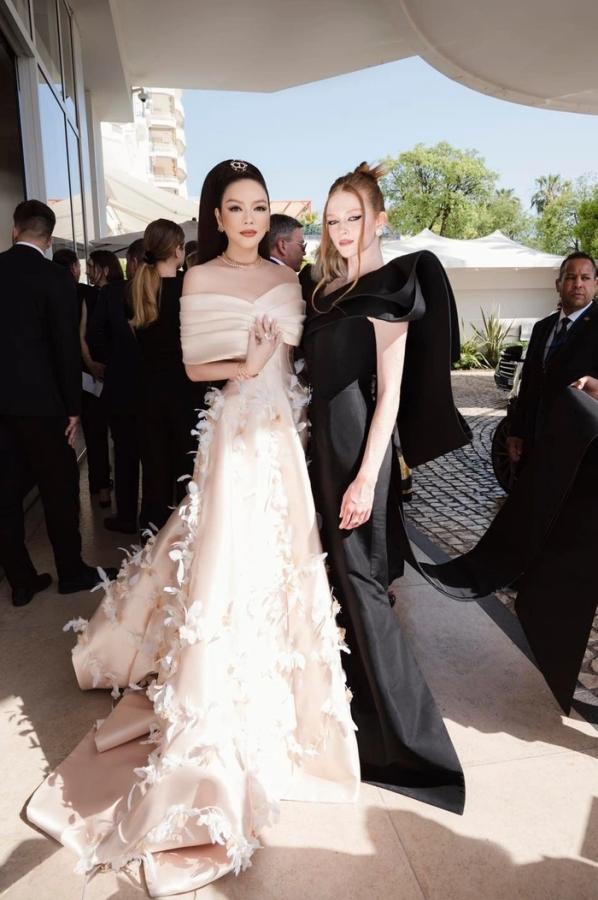 Trước giờ lên thảm đỏ, Lý Nhã Kỳ chụp ảnh bên Larson Thompson. Cả hai diện đầm dạ hội nhấn vào đường cắt ở vai và buộc tóc cao.