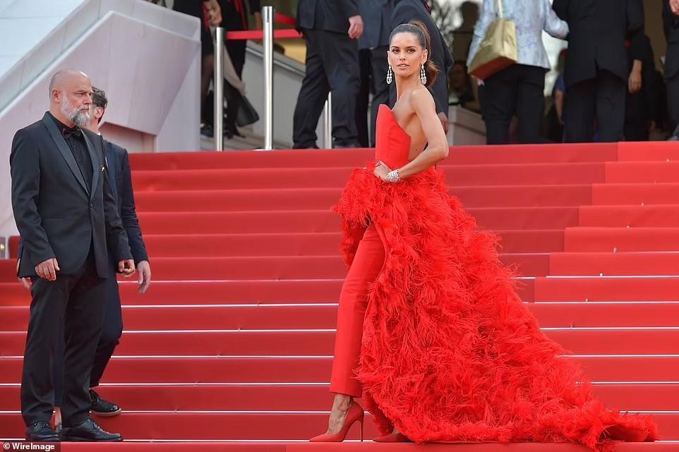 Izabel Goulart cũng đỏ rực từ đầu tới chân với áo choàng đính lông vũ màu đỏ phối cùng quần tây và giày cao gót ton-sur-ton.