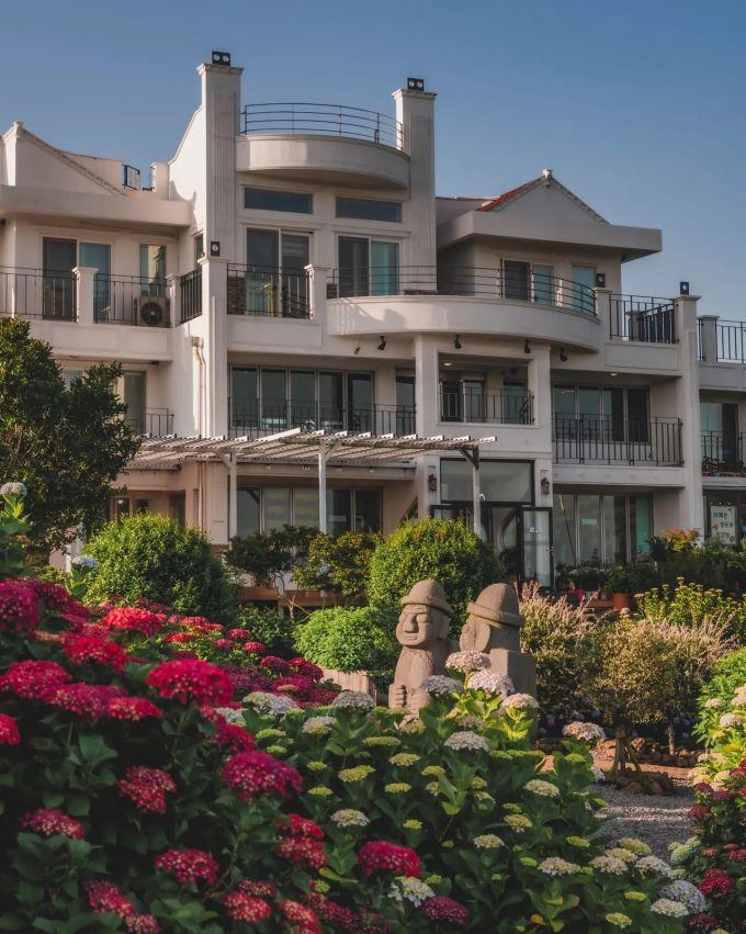 Manor Blanc là một trong những quán cà phê hút khách trên đảo nhờ vườn hoa theo mùa như: hoa trà vào mùa xuân, cỏ hồng vào mùa thu còn mùa hè thì cẩm tú cầu khoe sắc rực rỡ, cạnh những bức tượng Dol Hareubang làm bằng đá. Ảnh: Instagram sophie_phj.