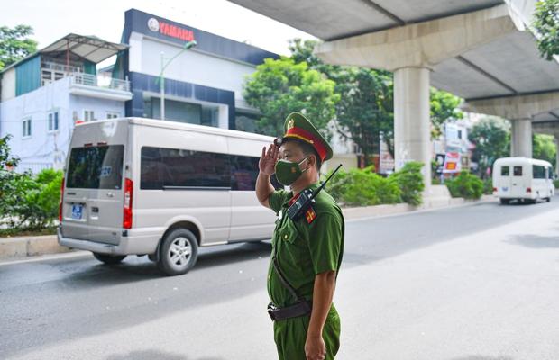 Một chiến sĩ làm nhiệm vụ trên đường đứng trang nghiêm, tiễn biệt đồng đội khi đoàn xe di chuyển qua