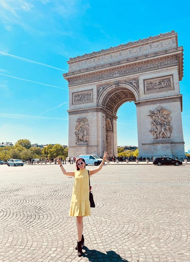 Chụp với Khải Hoàn Môn ở thủ đô Paris, vợ hơn tuổi của Bình Minh mặc đầm màu vàng chanh tươi hơn cả màu nắng.