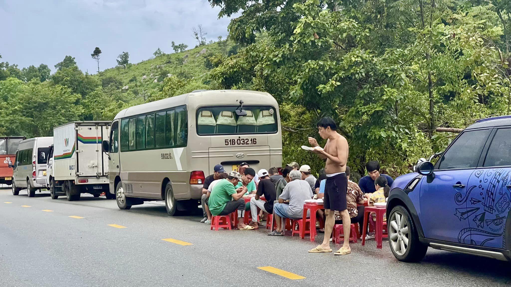 Thái Hòa cởi trần vừa đứng vừa tranh thủ ăn cơm hộp cùng cả ê-kíp để kịp giờ quay.