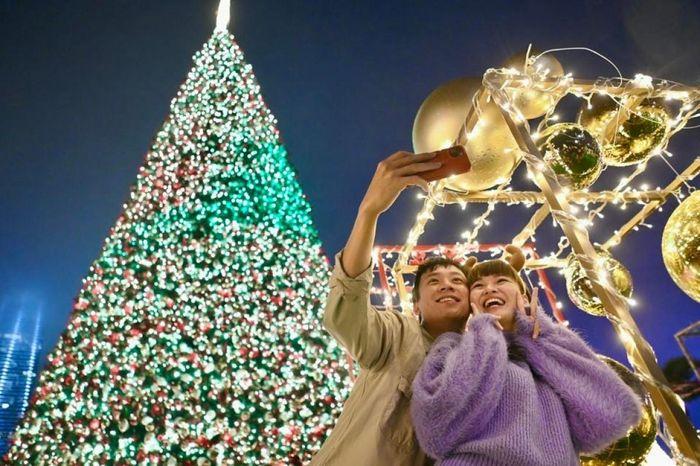 Một cặp đôi chụp ảnh selfie trước một cây thông Noel phát sáng ở Hong Kong, Trung Quốc.